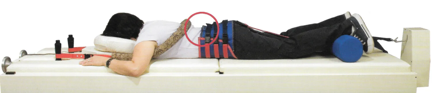 Patient lying on Vax-D spinal decompression table with pelvic harness